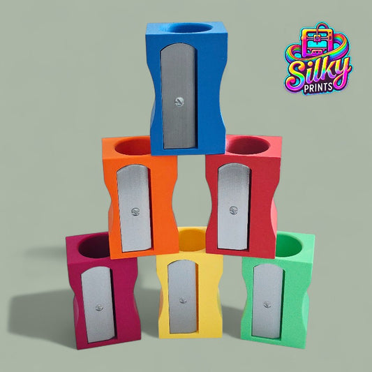 Colorful pencil sharpeners stacked on a gray background with 'Silky Prints' logo.