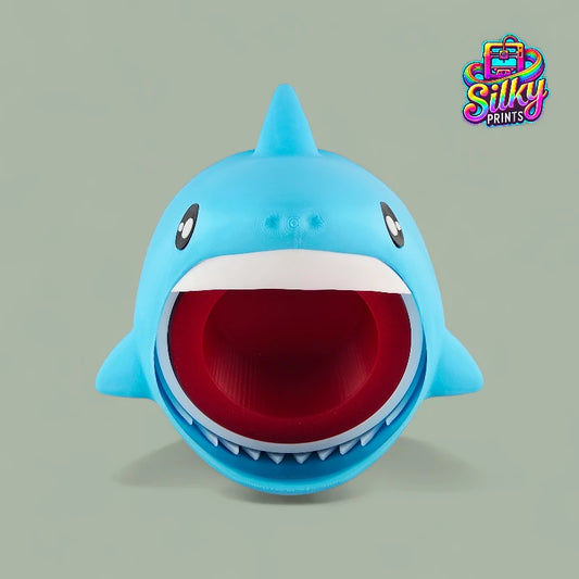 Blue shark-shaped toy with a red interior on a gray background, featuring the Silky Prints logo.