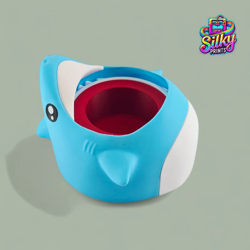 Blue shark-shaped container with a red interior on a light green background, featuring the Silky Prints logo.