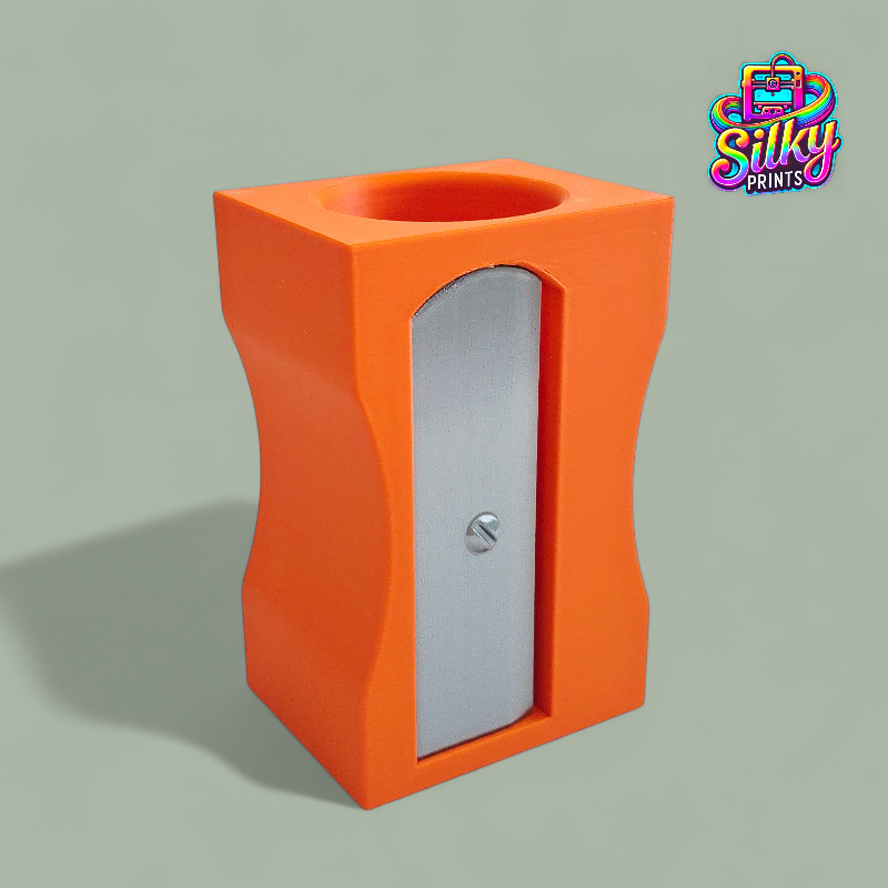 Orange pencil sharpener with a silver blade on a gray background, featuring the Silky Prints logo.