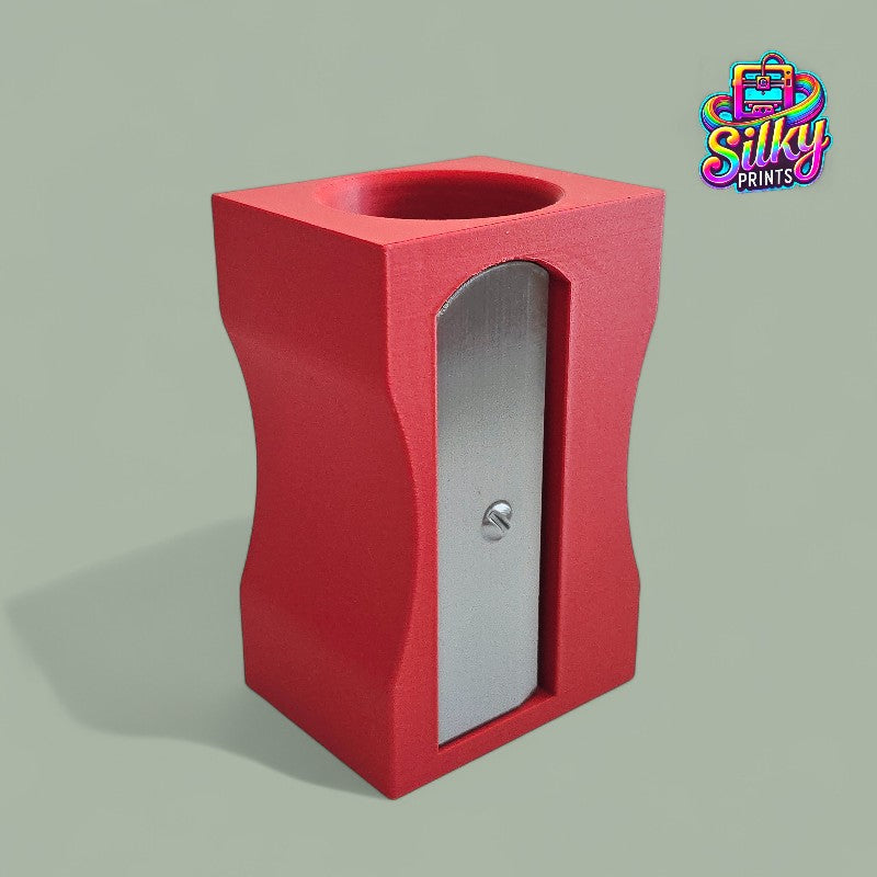Red pencil sharpener with a silver blade on a gray background, branded 'Silky Prints'.